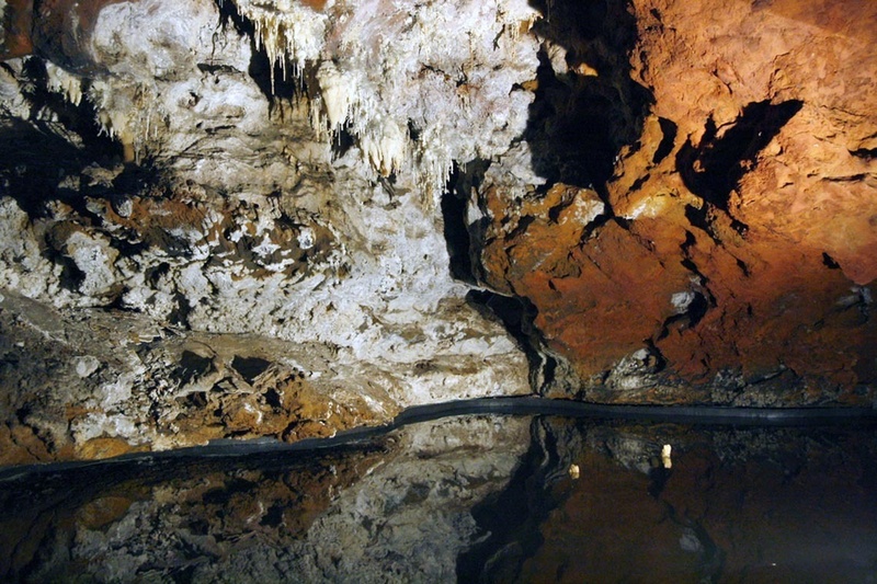 una cueva con rocas blancas y rojas y agua