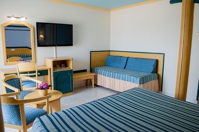 a hotel room with a striped couch and a flat screen tv