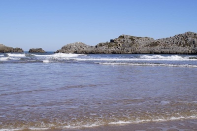 una playa con un montón de rocas en el fondo - 