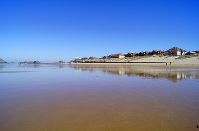 a beach with houses in the background and a blue sky - 