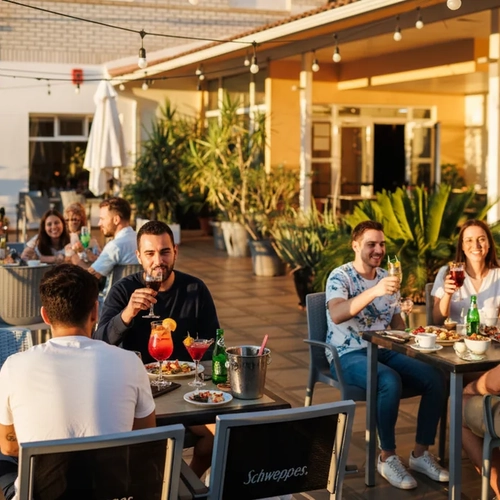 Guests enjoy drinks at an outdoor patio bar Hotel Acosta Ciudad de la Música.