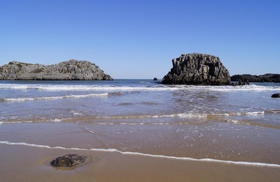 una playa con una gran roca en el fondo - 