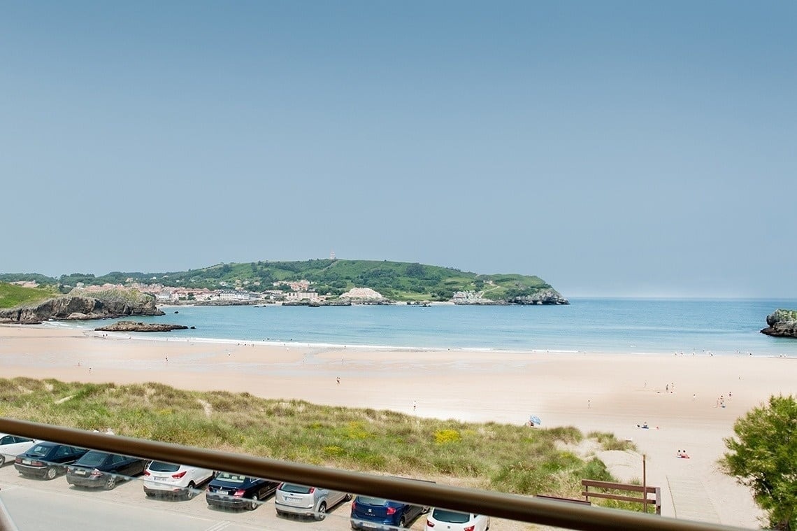 a view of a beach with cars parked in front of it