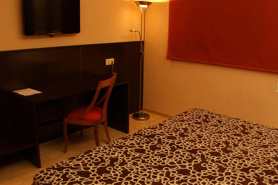 Escritorio con silla roja y cama cómoda en hotel. Hotel Acosta Ciudad de la Música