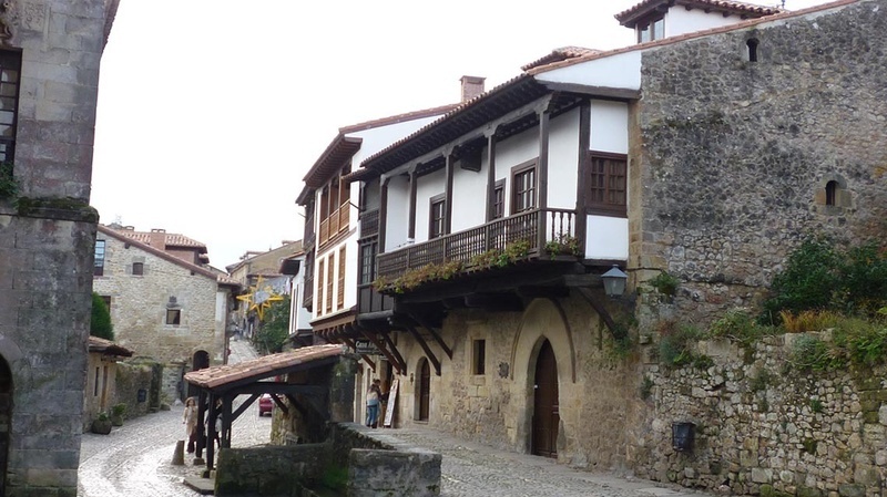 un edificio blanco con un balcón de madera está junto a un edificio de piedra