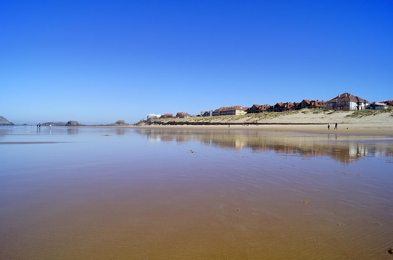 a beach with houses in the background and a blue sky
