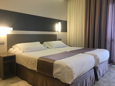 una habitación de hotel con dos camas y una cortina morada - 