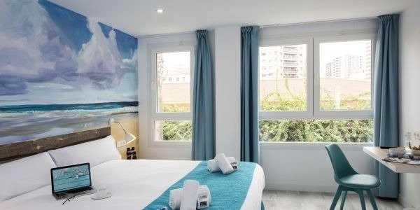 una habitación de hotel con una cama , una computadora portátil y una silla .