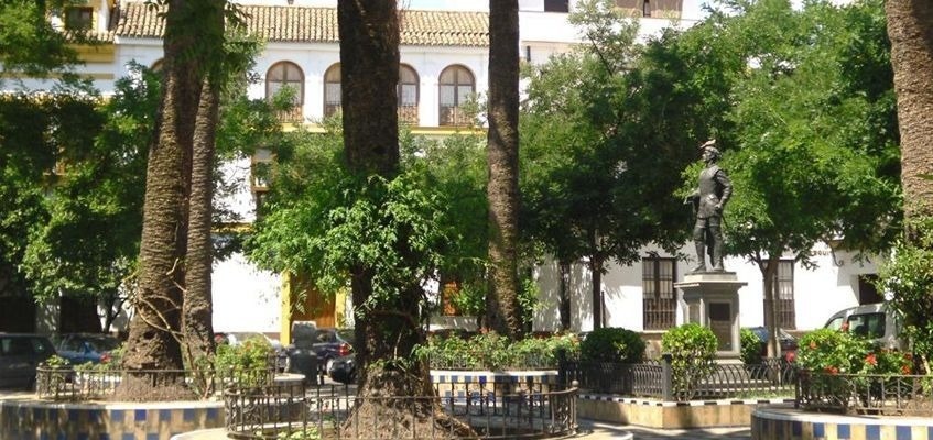 un parque con palmeras y una estatua de un hombre