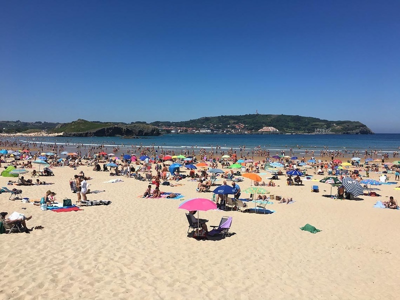 a beach filled with people and umbrellas on a sunny day
