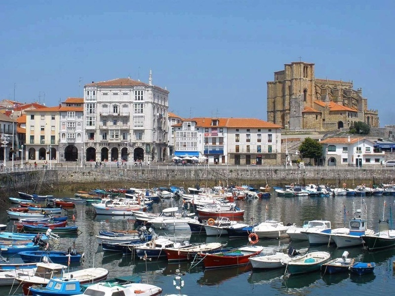 many boats are docked in a harbor with a large building in the background