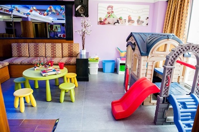 una sala de juegos para niños con un tobogán y una mesa - 