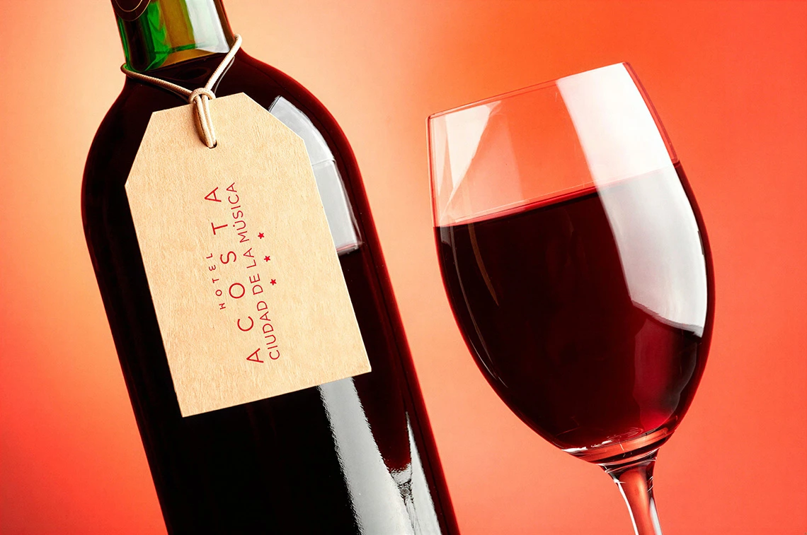 Vino tinto elegante con etiqueta "Hotel Acosta: Ciudad de la Música" y copa.