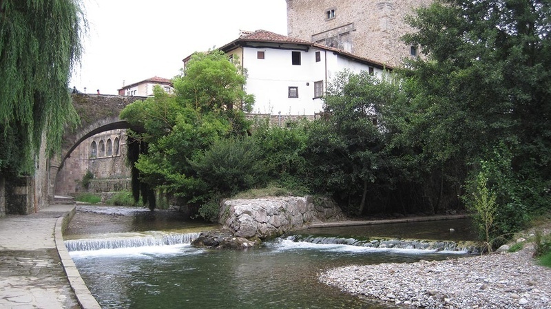 a bridge over a river with a white building in the background