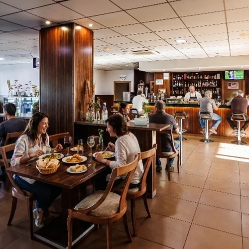 Hotel dining room with patrons enjoying meals at tables and at the bar. Hotel Acosta Ciudad de la Música