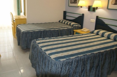 two beds in a hotel room with blue and white striped sheets