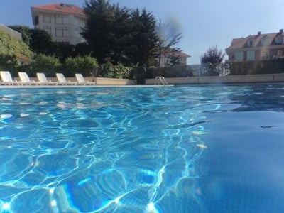 a swimming pool with chairs and buildings in the background - 