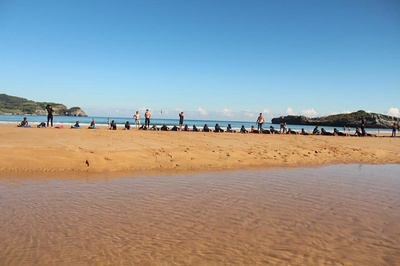 a group of people sit on a sandy beach near the ocean - 