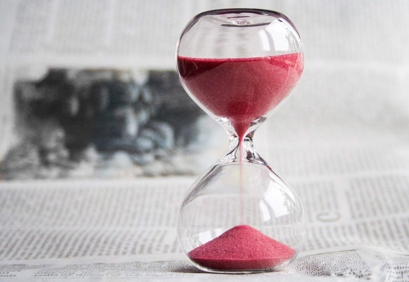 un sablier rempli de sable rouge se trouve sur un journal