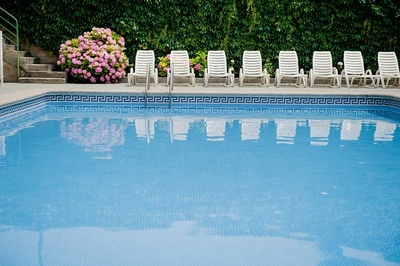 una piscina llena de sillas blancas y flores rosadas - 