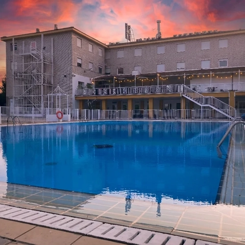 Hotel pool with sunset sky, spiral staircase, and balconies Hotel Acosta Ciudad de la Música