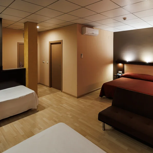 Comfortable hotel room with a large bed, sofa, and single bed. Hotel Acosta Ciudad de la Música