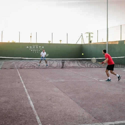 Hotel Hotel Acosta Ciudad de la Música guests enjoy tennis on a beautiful outdoor court at sunset.