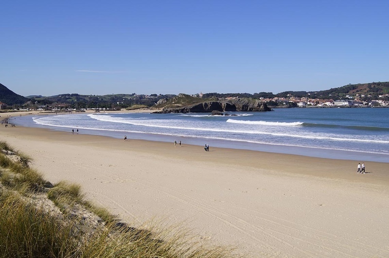 un grupo de personas camina por la playa en un día soleado