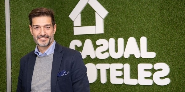 un hombre con traje y corbata está parado frente a un cartel que dice casual tele2