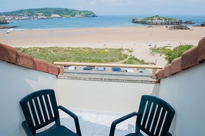 a view of a beach from a balcony with two chairs