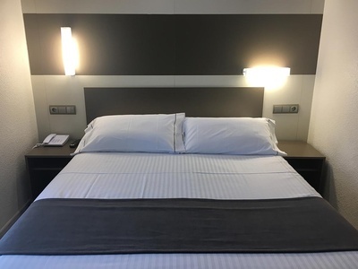 una cama con sábanas blancas y almohadas en una habitación de hotel