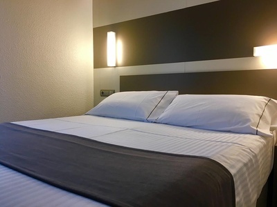 a bed with white sheets and pillows in a hotel room