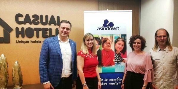 un grupo de personas están paradas frente a un cartel que dice casual hotels .