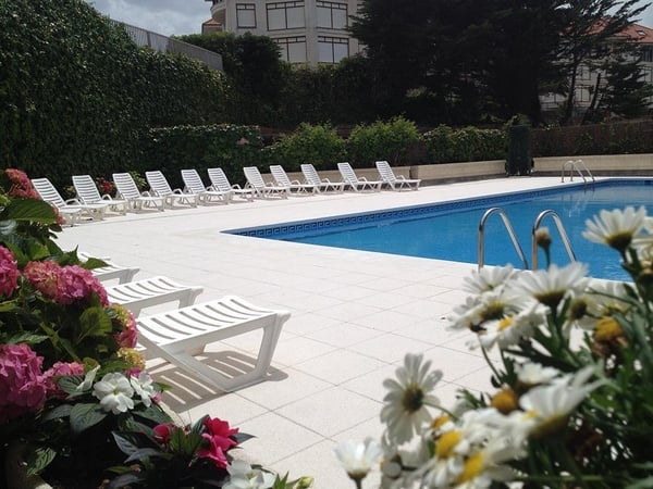una piscina rodeada de flores y sillas blancas
