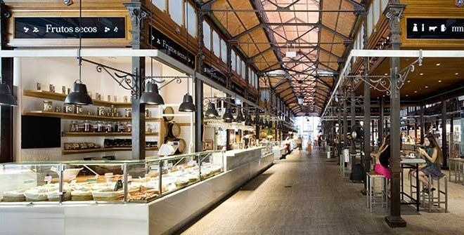 una mujer está sentada en una mesa en un mercado de alimentos .