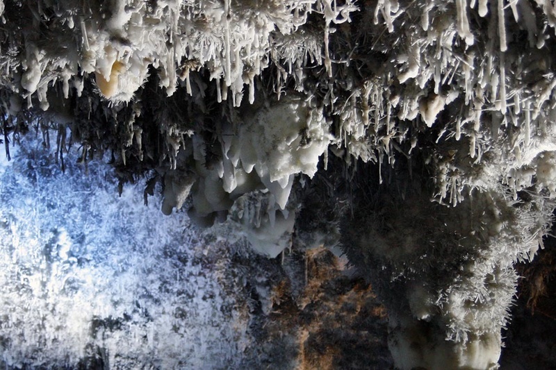 un montón de rocas blancas y negras cuelgan del techo de una cueva