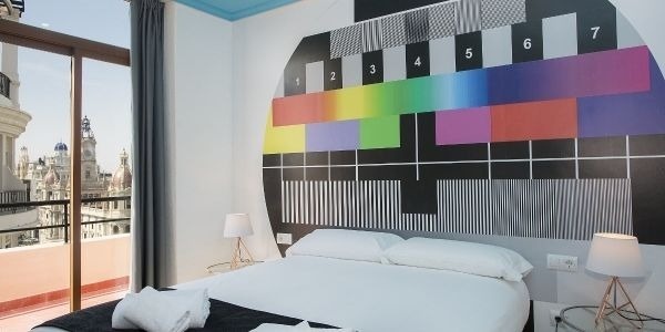 una habitación con una cama , lámparas y una pintura de un televisor en la pared .