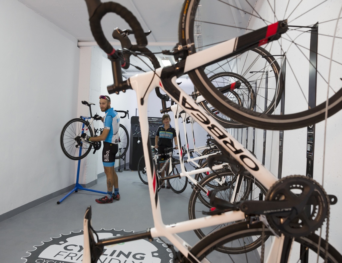a man is working on a bicycle in a room with a sign that says cycling friends
