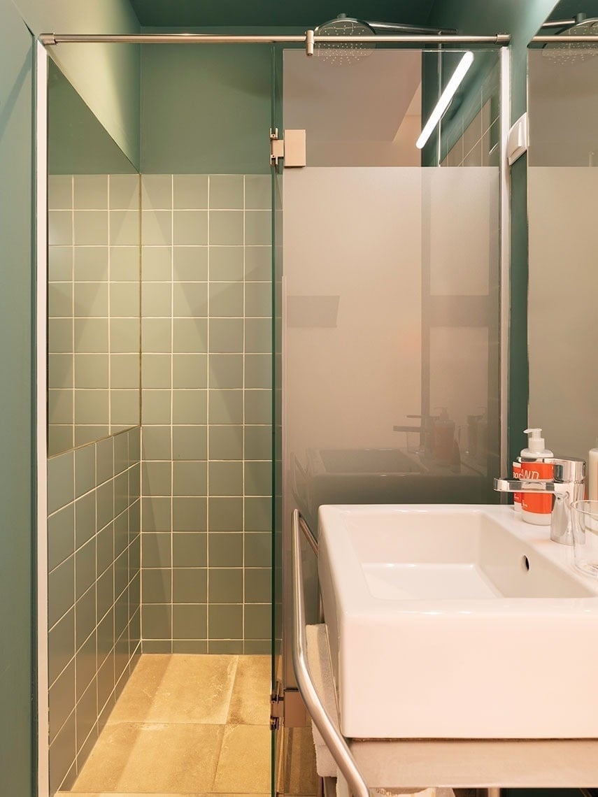 Modern bathroom with glass shower, sink, e azulejos verde.