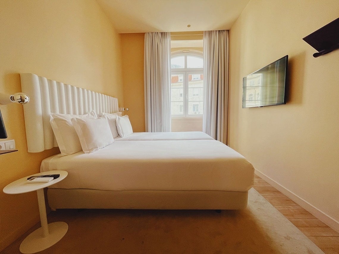 TEST3: Copia 4 - Quarto de hotel moderno com duas camas, TV e janela com vista.