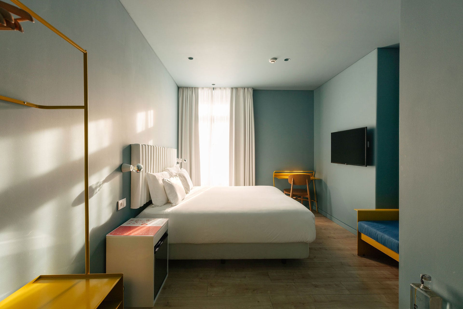 Quarto de hotel moderno com cama de casal, escrivaninha e TV - Quartos | Esqina Cosmopolitan Lodge