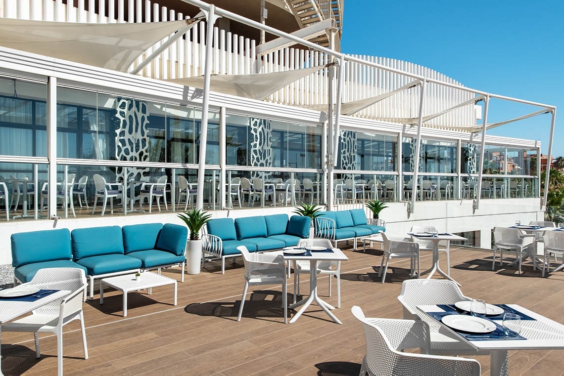 une terrasse avec des canapés bleus et des tables blanches