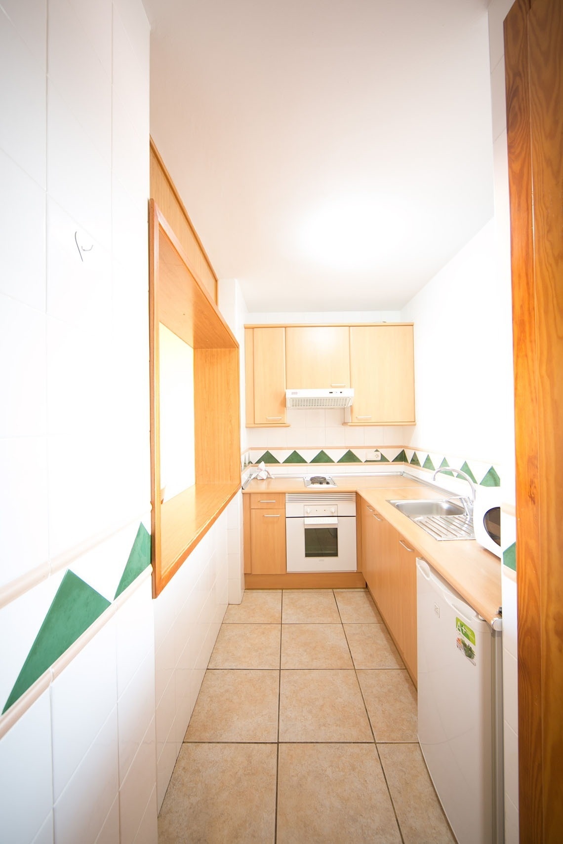 una cocina con gabinetes de madera y azulejos verdes