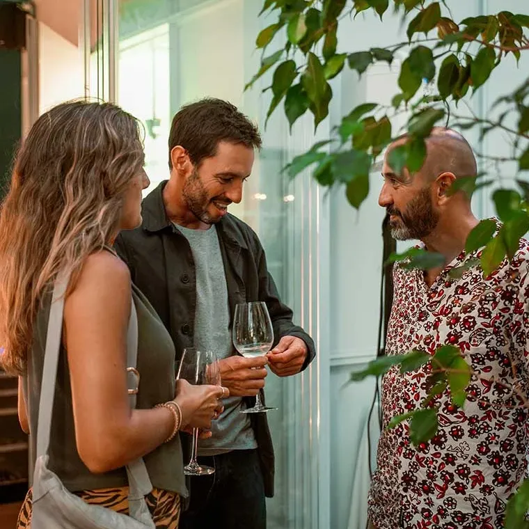 Tres personas conversando y disfrutando de copas de vino en un evento de hotel Esqina: Cosmopolitan.