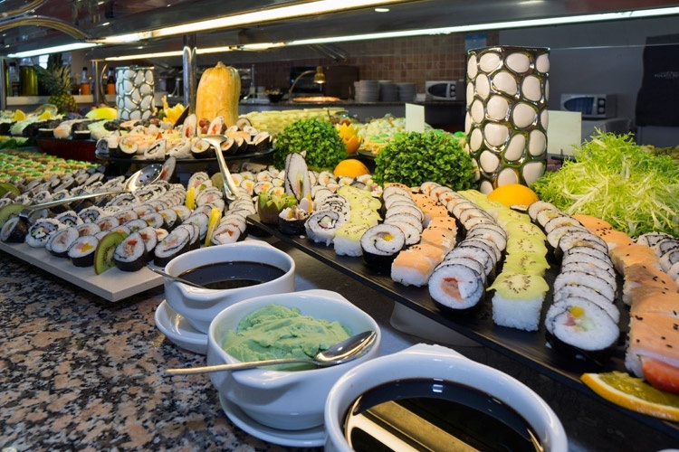 un buffet lleno de sushi y salsas en un restaurante