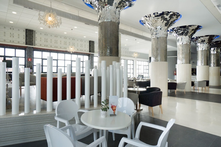 white chairs and tables in a room with silver columns