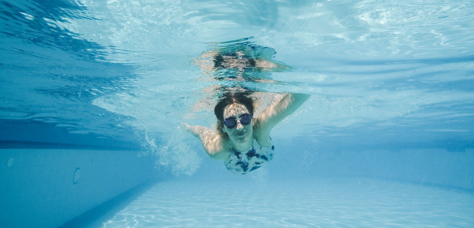 a woman wearing goggles is swimming underwater in a pool