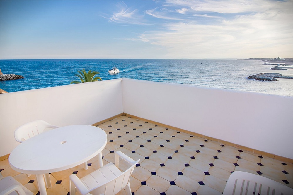 a white table and chairs on a balcony overlooking the ocean