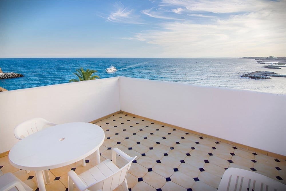 a white table and chairs on a balcony overlooking the ocean