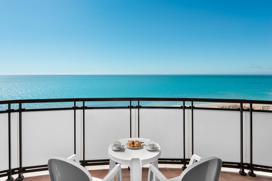 a balcony with a table and chairs overlooking the ocean